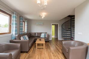 A living room with a brown leather sofa, a wooden coffee table, and a staircase.