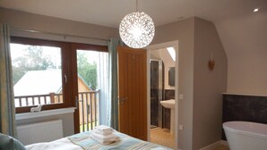 A bedroom with a bed, a bathroom with a bathtub, and a view of the outside. - Lord Galloway 35 (Newton Stewart)