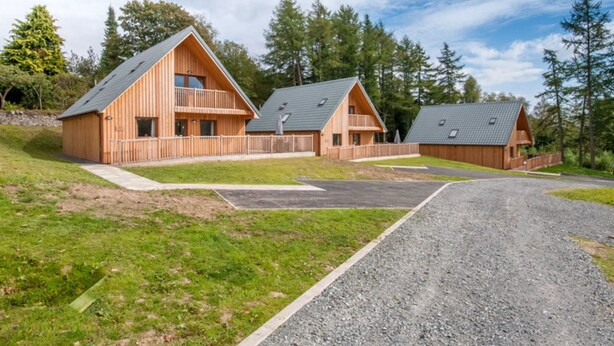 A modern wooden cabin complex with multiple units, each featuring a balcony and a sloped roof. - Lord Galloway 35 (Newton Stewart)