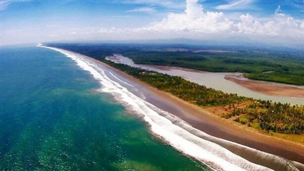 An aerial view of a coastal landscape with a beach, forested area, and a river. - Hotel La Isla (Parrita)