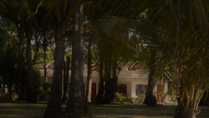 A building with a tiled roof, surrounded by palm trees and greenery. - Hotel La Isla (Parrita)