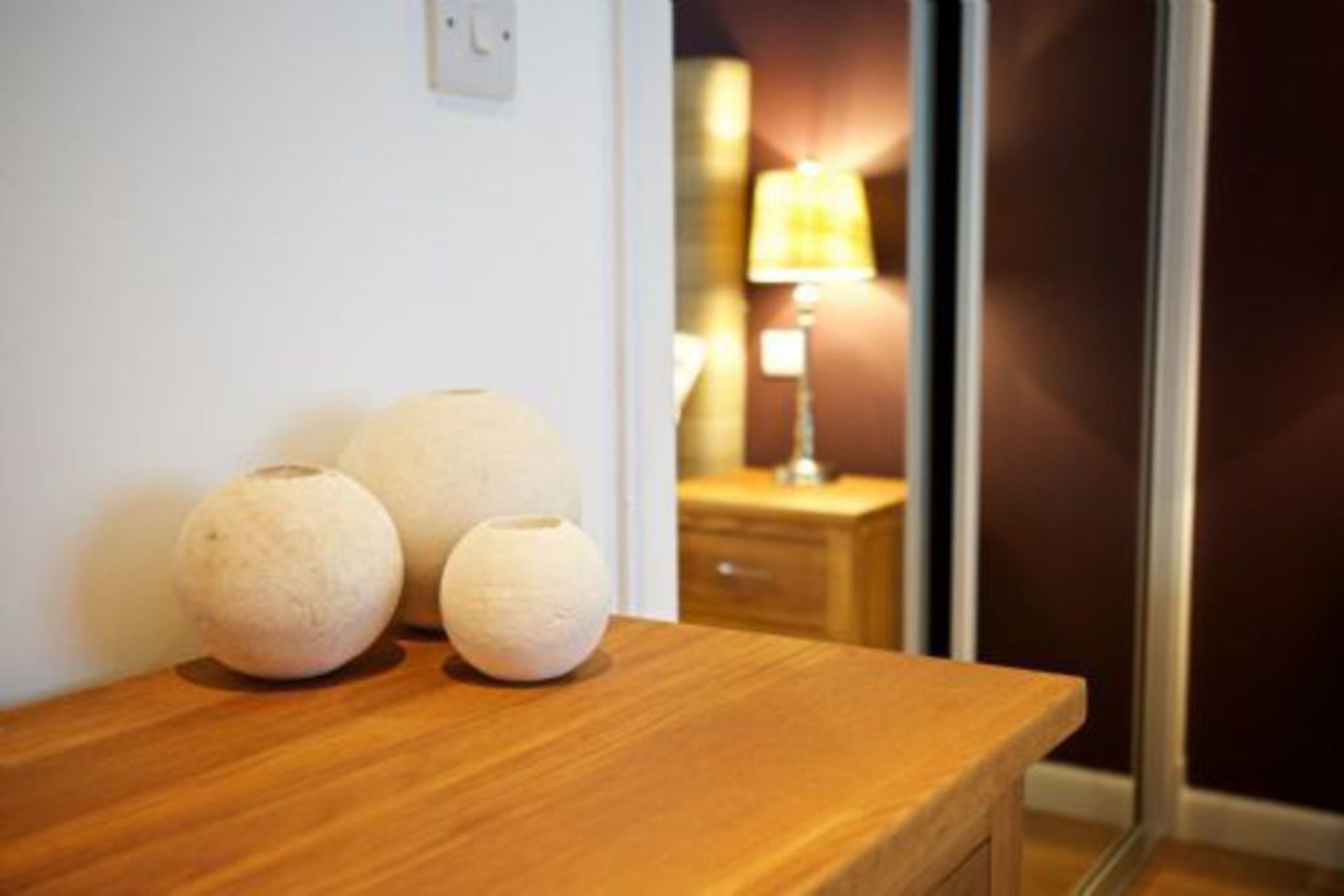 A wooden bedside table with three spherical objects on it.