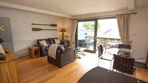 A modern living room with a sofa, a glass table, and a view of the outside. - Beinn Fhada (Aberfeldy)