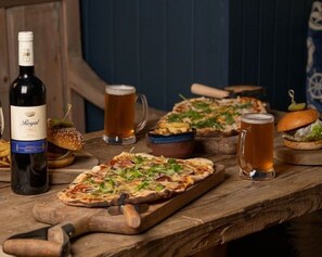A wooden table with pizzas, beer mugs, and a bottle of wine. - Beinn Fhada (Aberfeldy)