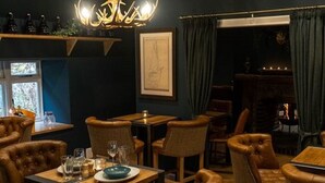 A cozy restaurant interior with leather chairs, wooden tables, and a chandelier. - Taymouth Marina - Ben Cruachan (Aberfeldy)