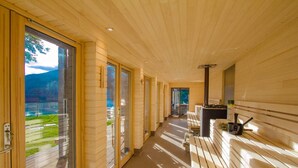 A modern interior with a wooden ceiling, large glass doors leading to a view of a lake and mountains, and a fireplace with a chimney. - Taymouth Marina - Ben Cruachan (Aberfeldy)