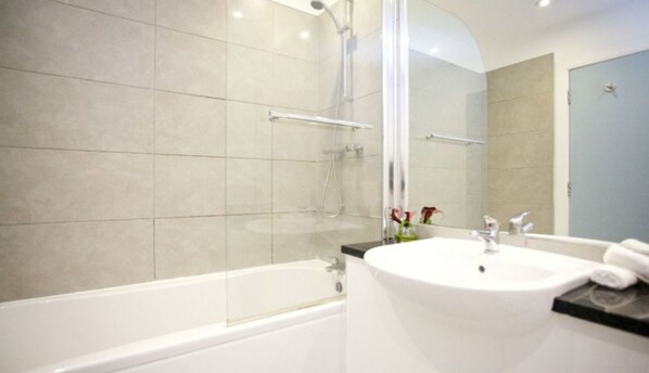 A modern bathroom with a bathtub, a sink, and a shower area.