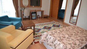 A hotel room with a bed, a desk, a chair, a TV, and a large mirror. - Hasan Celebi Otel (Siverek)