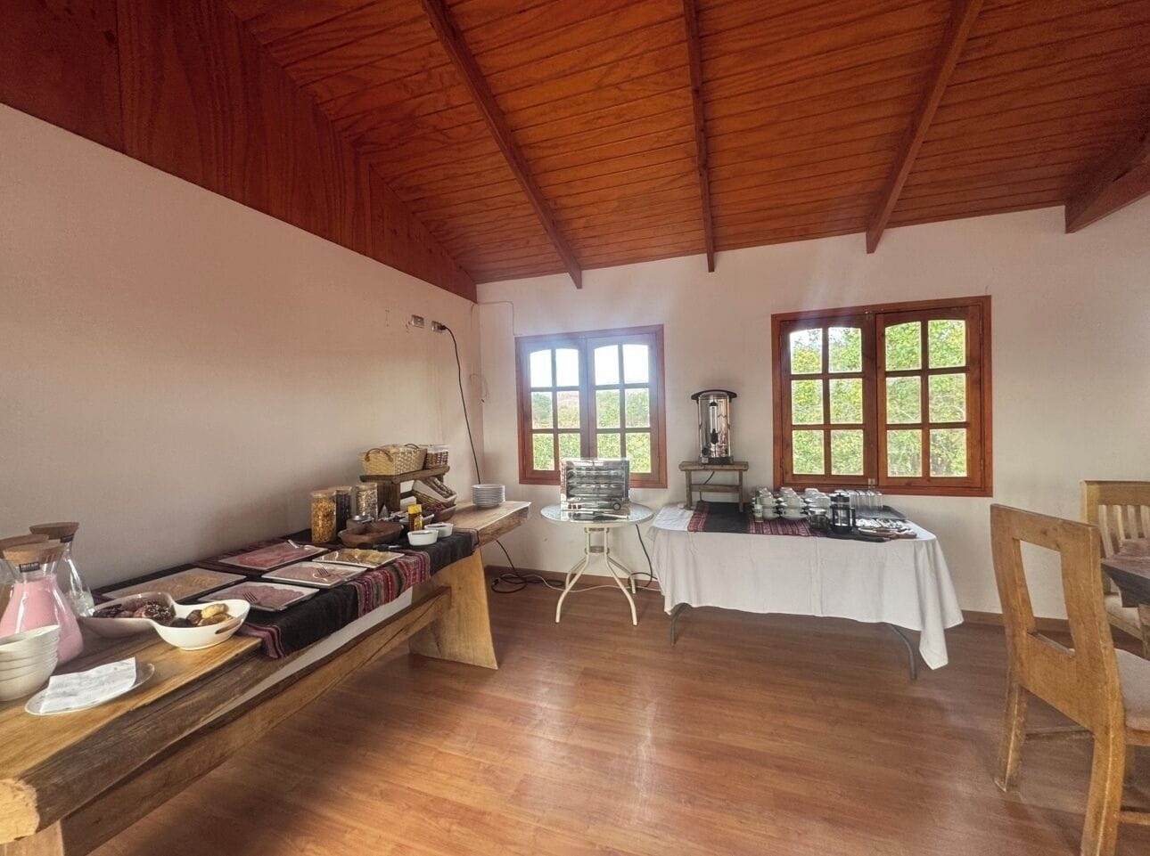 A dining area with wooden tables, a long bench, and a coffee station.