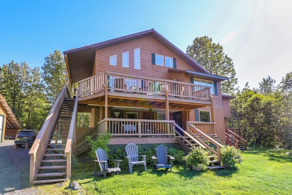 A two-story wooden cabin with a balcony, a staircase, and outdoor seating.