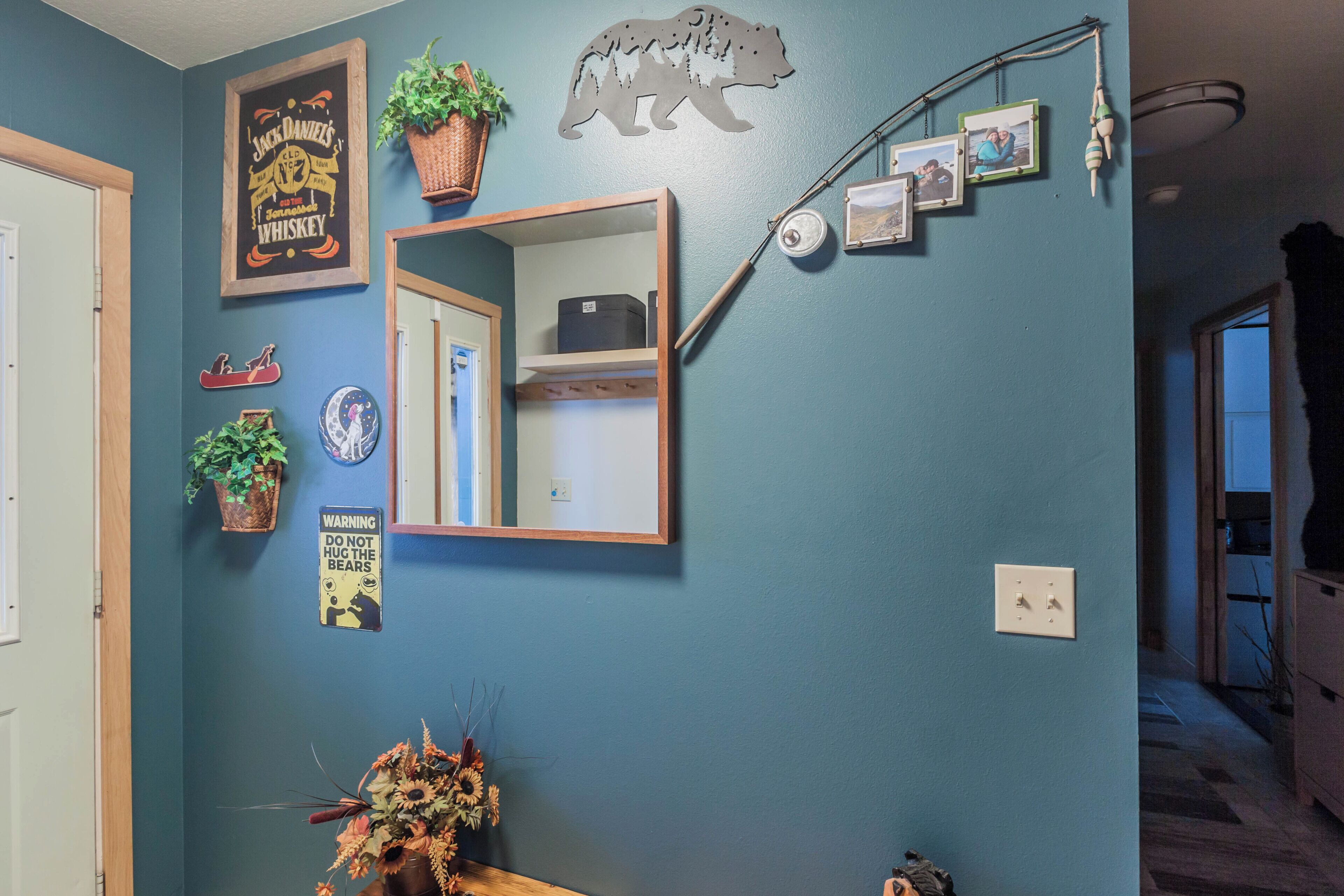 Een kamer met een blauwe wand, een spiegel, een beren decoratie, een waarschuwingsbord en een plant.