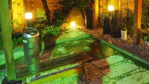 A garden with a wooden pergola, a small pond, and potted plants. - Tsutiu Onsen Yamaneya Ryokan (Fukushima)