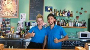 A bar area with a wooden counter, shelves with bottles, and a chalkboard menu. - Hostal Ardoi (Zizur Mayor)