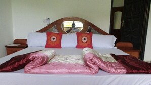 Un lit avec une tête de lit en bois, deux oreillers à motifs circulaires et une couverture pliée en deux.