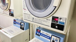 A laundry facility with a front-loading washing machine, a coin-operated dryer, and a scale for weighing laundry.