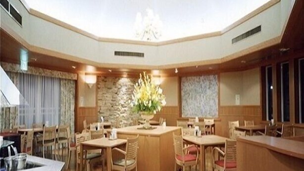 A spacious dining area with a high ceiling and skylight, featuring wooden furniture and a central floral arrangement.