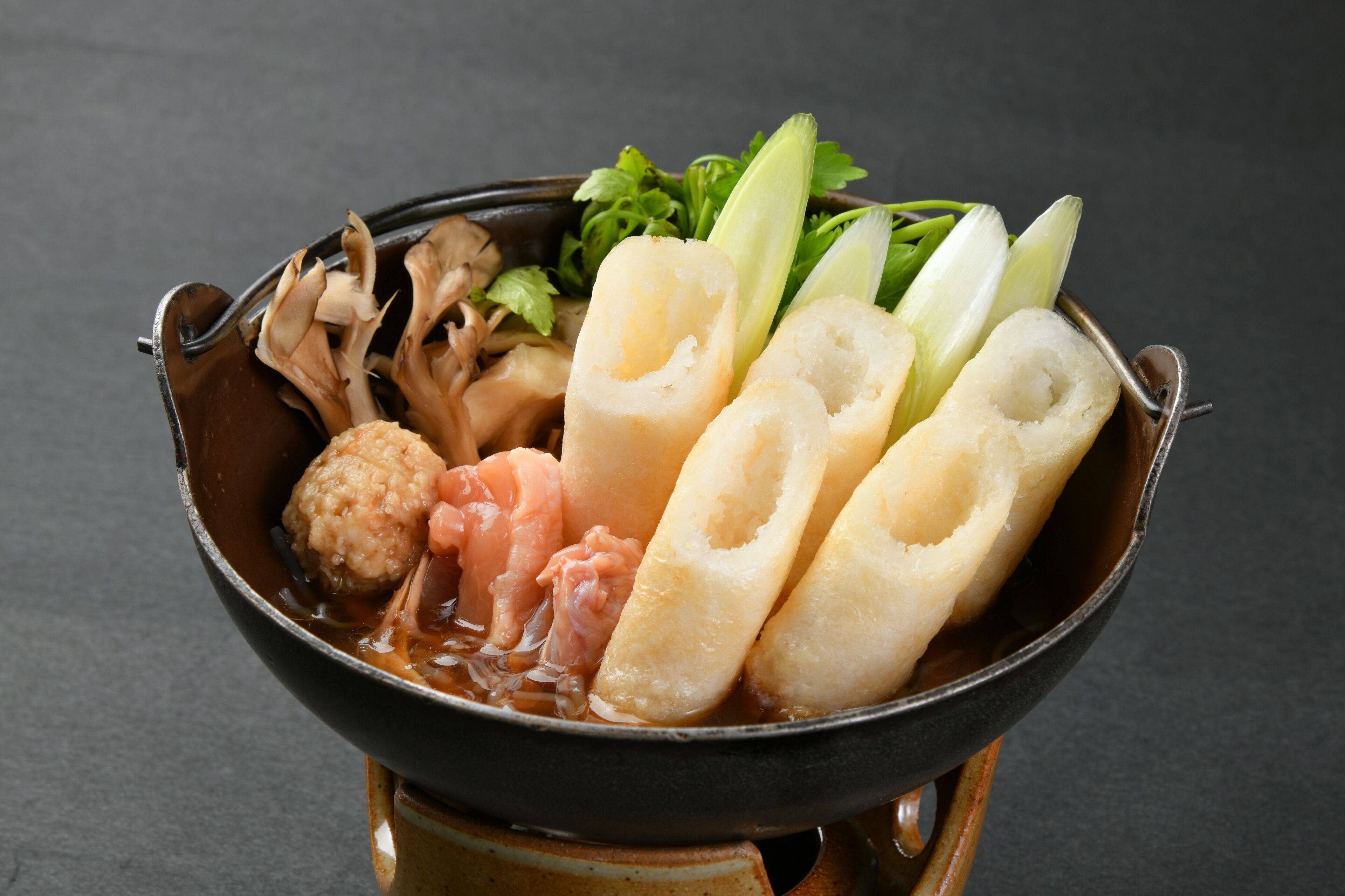 A bowl of hot pot with various ingredients like mushrooms, meat, and vegetables.