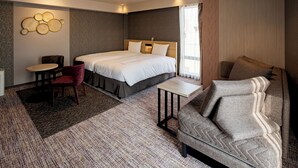 Une chambre d’hôtel moderne avec un grand lit, un canapé, une petite table et une chaise.