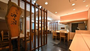 L’intérieur d’un restaurant, avec des meubles en bois, une grande enseigne en bois ornée de calligraphies et un design moderne au niveau du plafond.