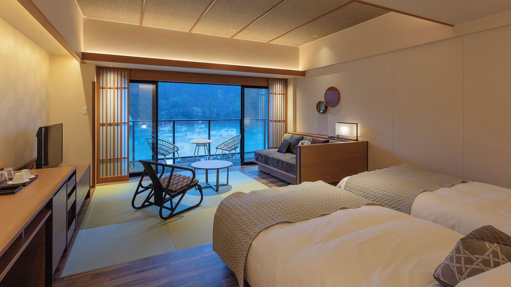 A hotel room with a balcony, a bed, a desk, and a TV.