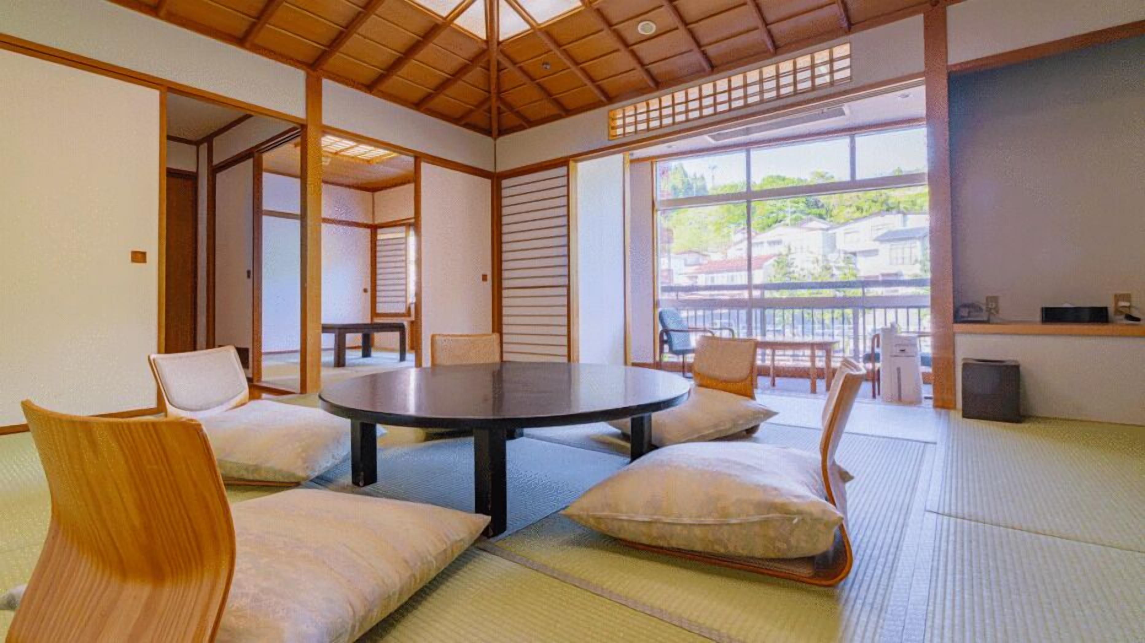 A traditional Japanese-style room with tatami flooring, a round table, and low wooden furniture.