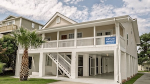 A two-story beachfront property with a balcony, a staircase, and a sign indicating it is for sale. - At Last Apartment 5 (Murrells Inlet)
