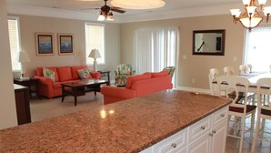A kitchen with a granite countertop, white cabinetry, and a dining area with a white table and chairs. - Bermuda Breeze C Holiday Home Holiday home 8 (North Myrtle Beach)