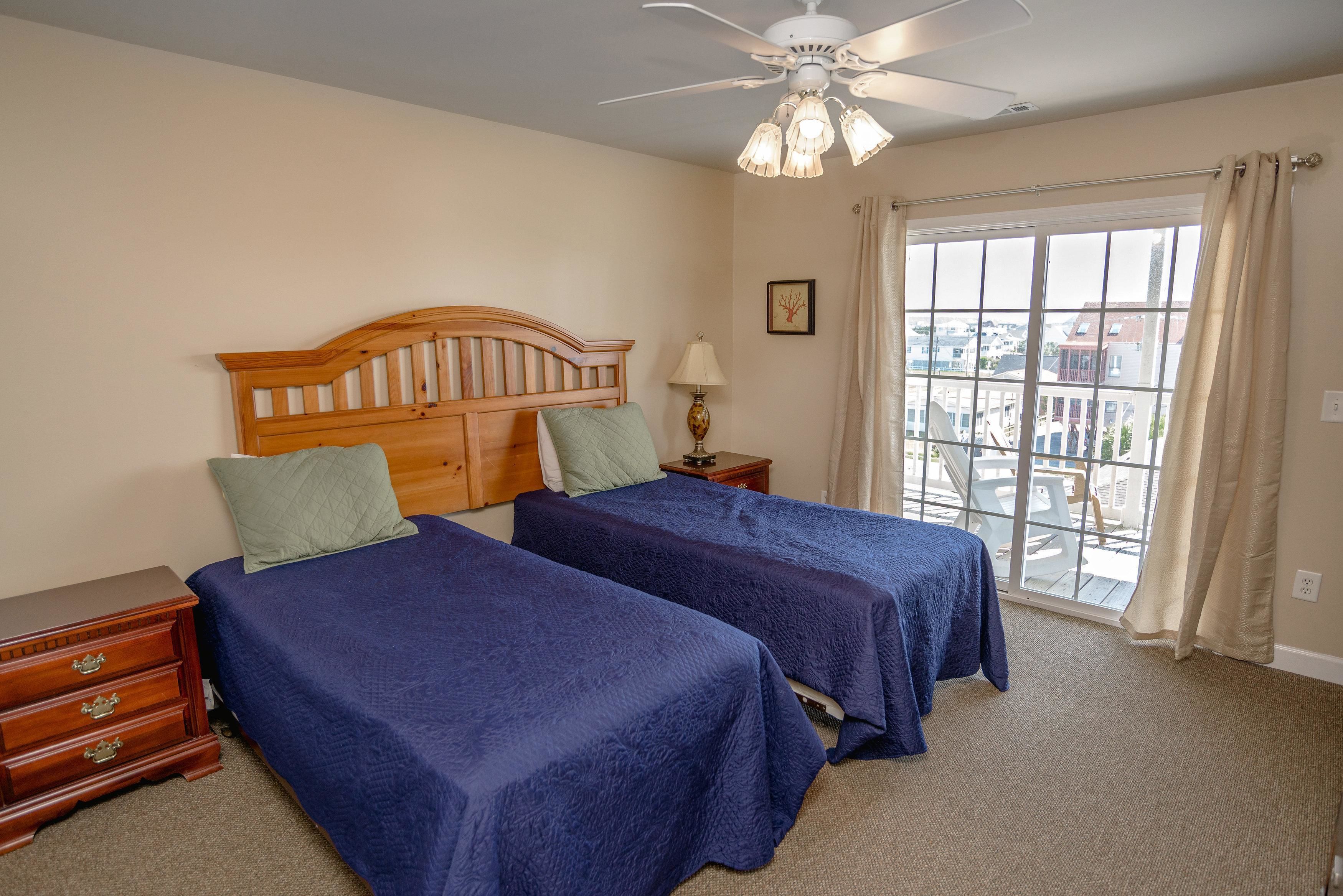 A bedroom with two beds, a wooden headboard, a nightstand, a lamp, and a view of the city through a large window.