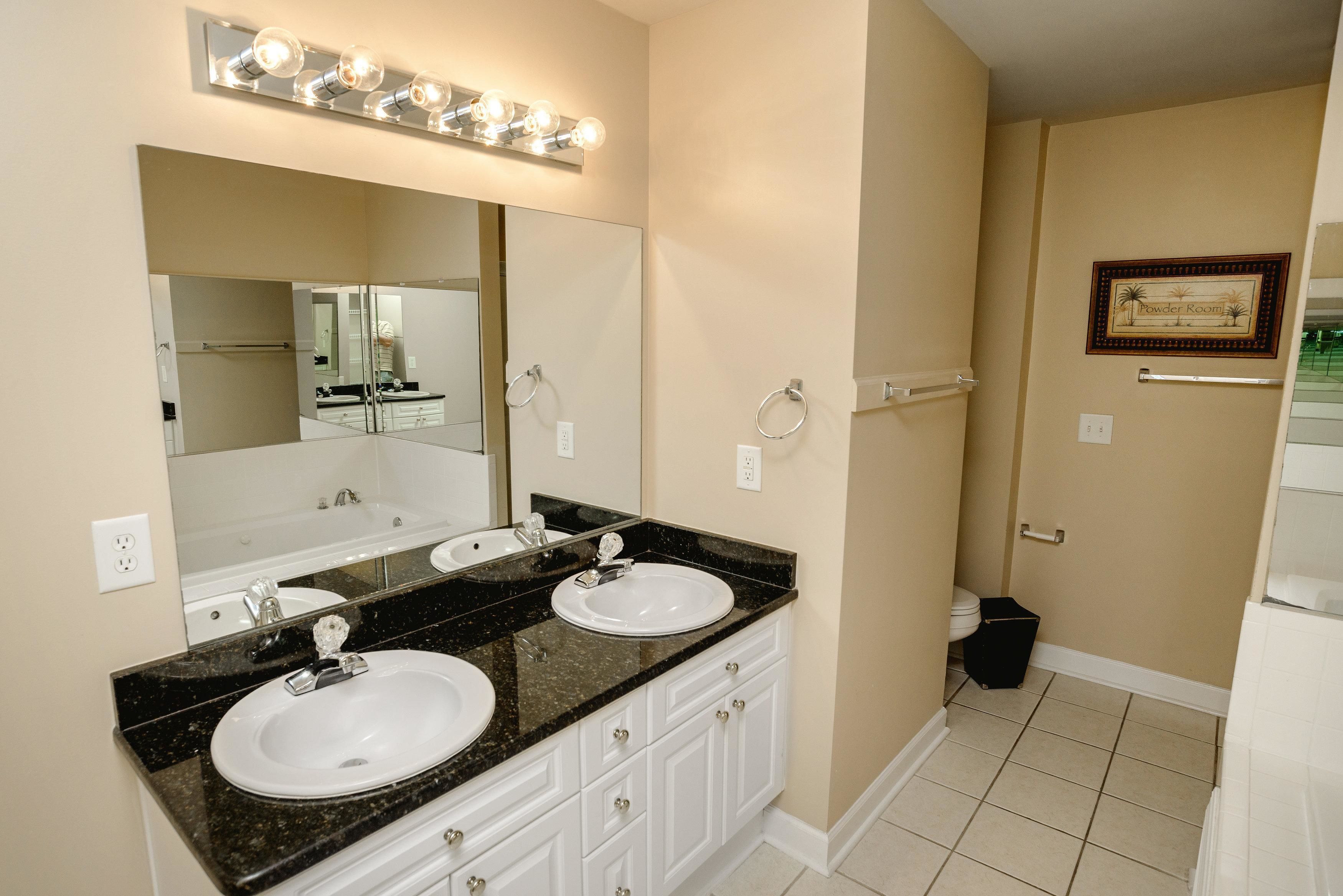 A bathroom with two sinks, a large mirror, and a vanity with drawers.