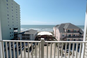 Blick vom Balkon auf einen Strand mit Gebäuden im Vordergrund.