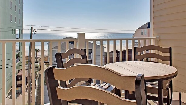 A balcony with a table and chairs, overlooking a beach and ocean. - Cherry Grove 406 Villa Villa 6 (North Myrtle Beach)