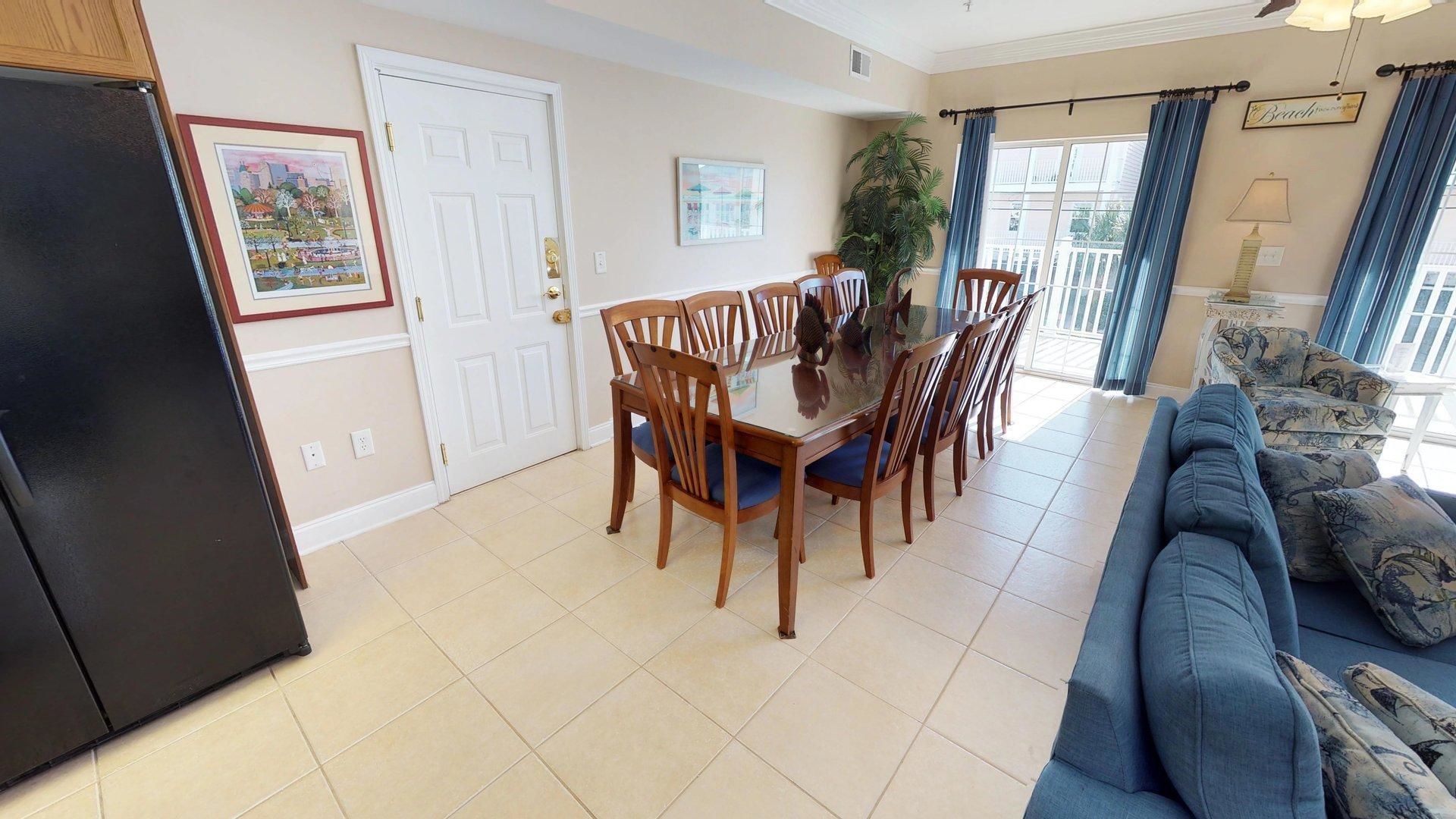 A dining area with a wooden table and chairs, a blue sofa, and a refrigerator.