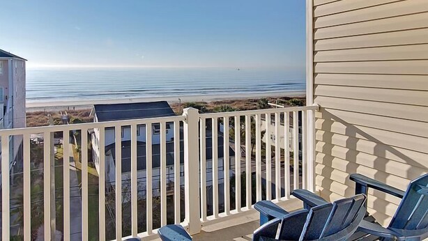 A balcony with a view of the ocean, a table, and two chairs. - Coconut Grove 402 Villa Villa 6 (North Myrtle Beach)