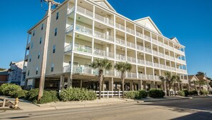 A multi-story hotel with balconies, a parking garage, and palm trees. - Coconut Grove 403 Villa Villa 5 (North Myrtle Beach)
