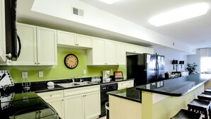 A modern kitchen with white cabinets, a black countertop, a built-in dishwasher, and a coffee maker. - Coconut Grove 403 Villa Villa 5 (North Myrtle Beach)