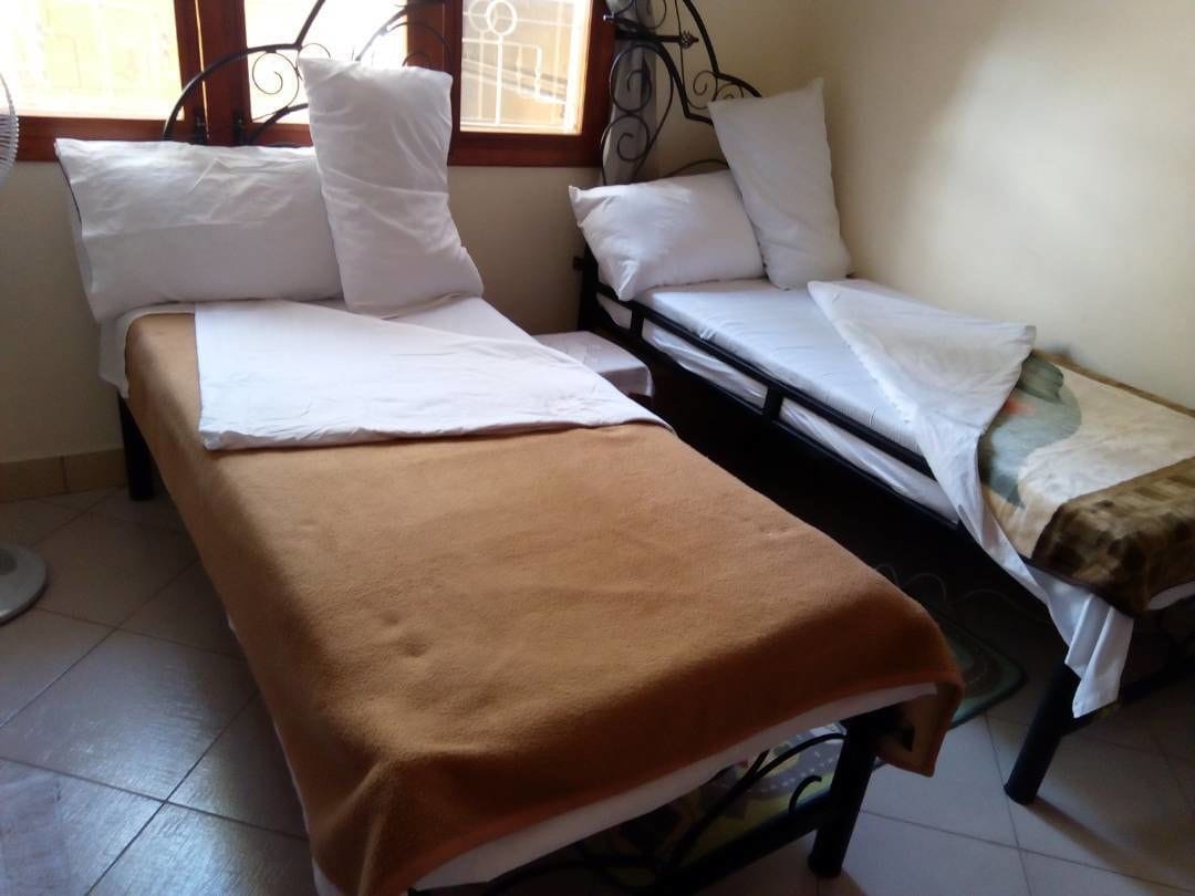 Una habitación con dos camas, una con una manta marrón y la otra con ropa de cama blanca.