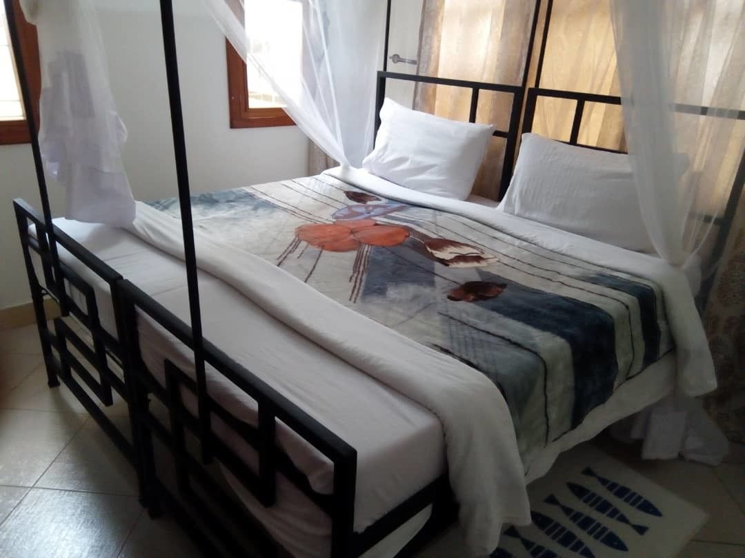 A bed with a mosquito net, white pillows, and a floral bedspread.