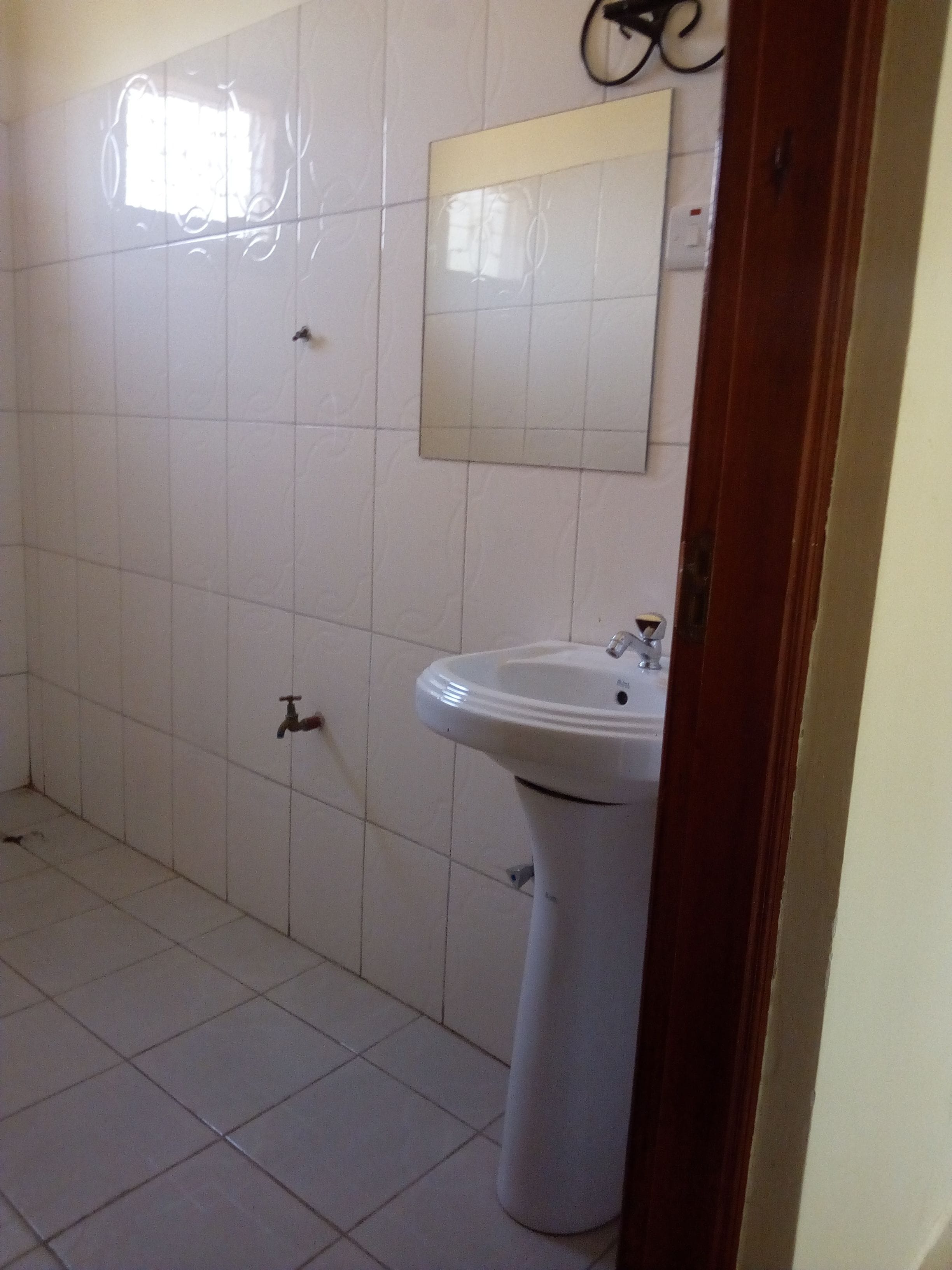 Un baño con paredes de azulejos blancos, un lavamanos y un espejo.