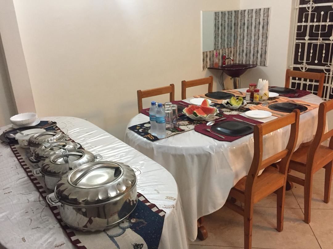 Una mesa de comedor dispuesta con platos, cubiertos y una botella de agua.