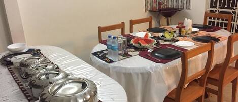 A dining table set with plates, cutlery, and a water bottle.