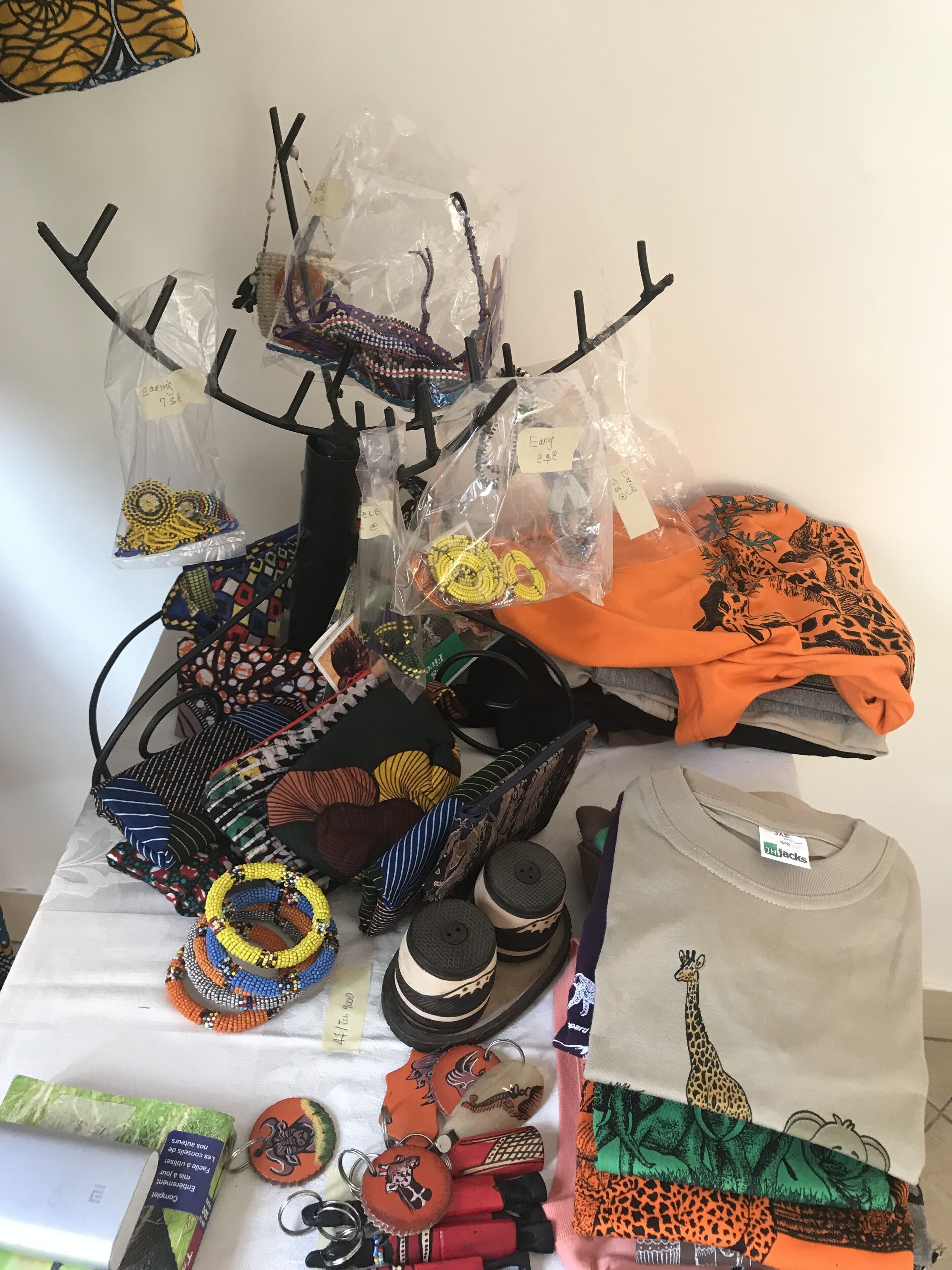 A table with various bags, hats, and a t-shirt with a giraffe design.
