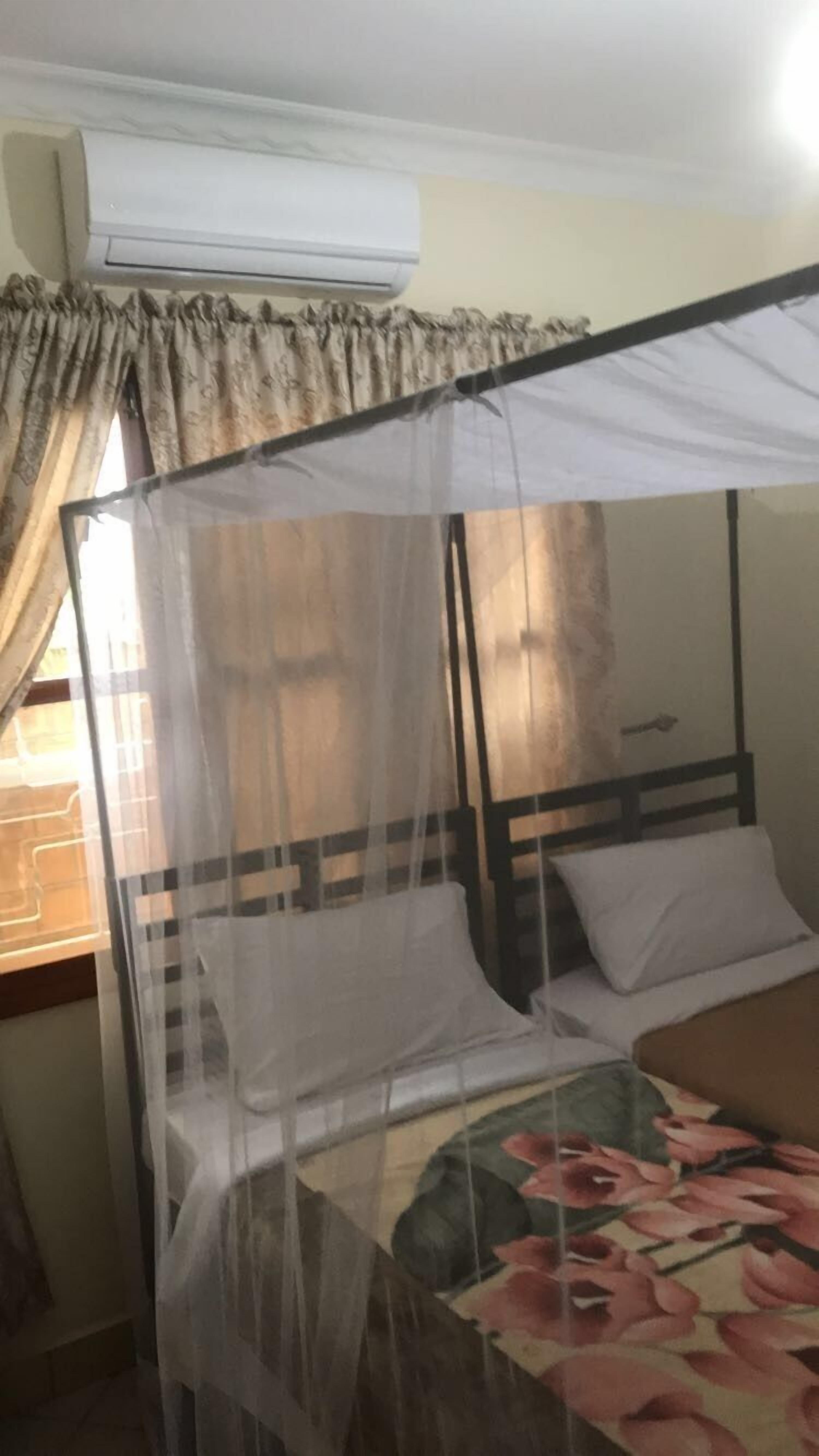 A bed with a mosquito net, white pillows, and a floral bedspread.