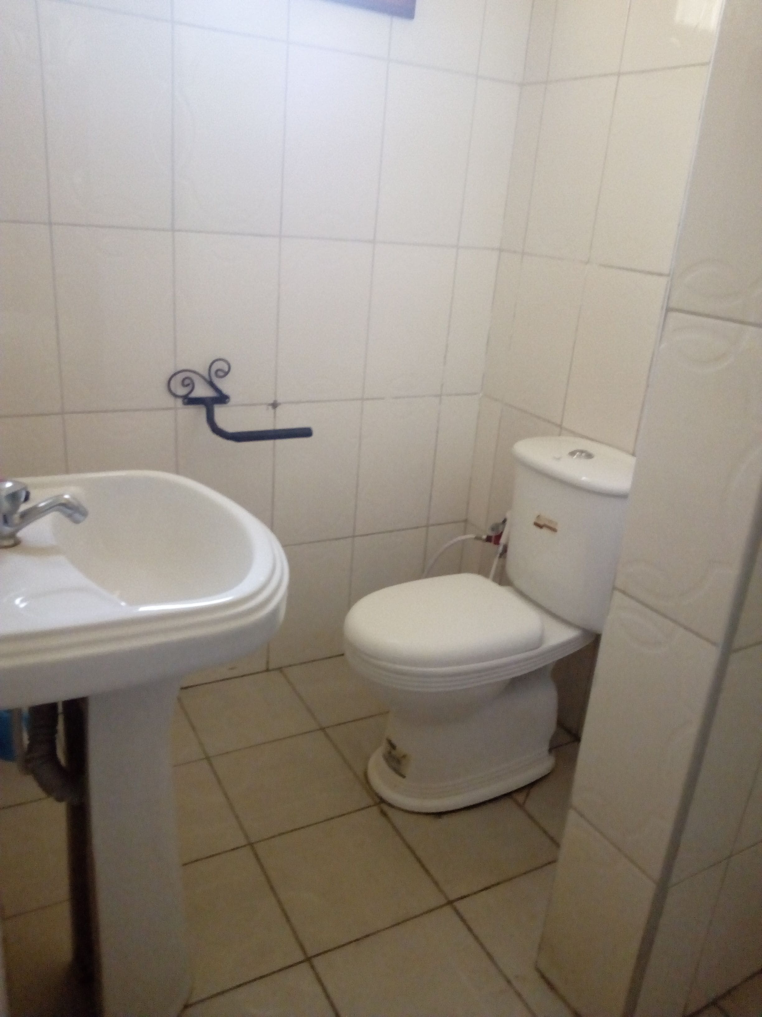 Une salle de bain avec un lavabo blanc, des toilettes et des murs carrelés.