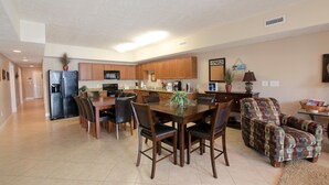 A spacious kitchen with wooden cabinets, a dining table with chairs, and a living area with a patterned sofa. - Myrtle Beach 201B Villa Villa 4 (Myrtle Beach)