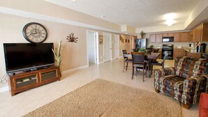 A spacious living room with a flat-screen TV, a dining area with chairs, and a kitchen with wooden cabinets and appliances. - Myrtle Beach 201B Villa Villa 4 (Myrtle Beach)