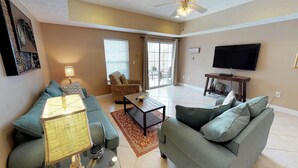 A living room with a sofa, a coffee table, a lamp, and a TV.