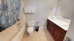 A bathroom with a bathtub, toilet, and vanity with a mirror.
