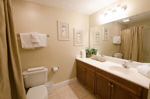 Een badkamer met toilet, wastafel, spiegel en handdoekhouder.