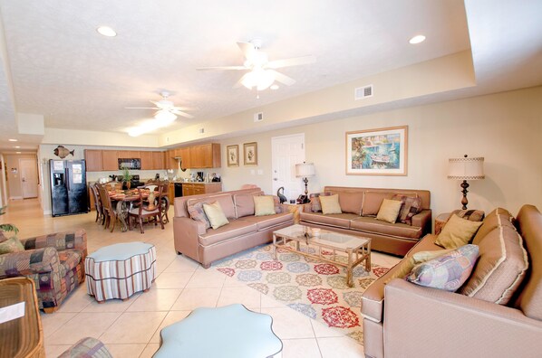 A spacious living room with a large sofa, a coffee table, and a dining area with chairs and a table.