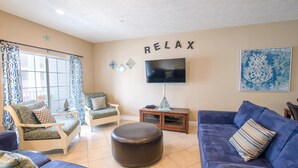 Un salón con televisor, un cartel que dice 'RELAX' y un adorno en la pared.